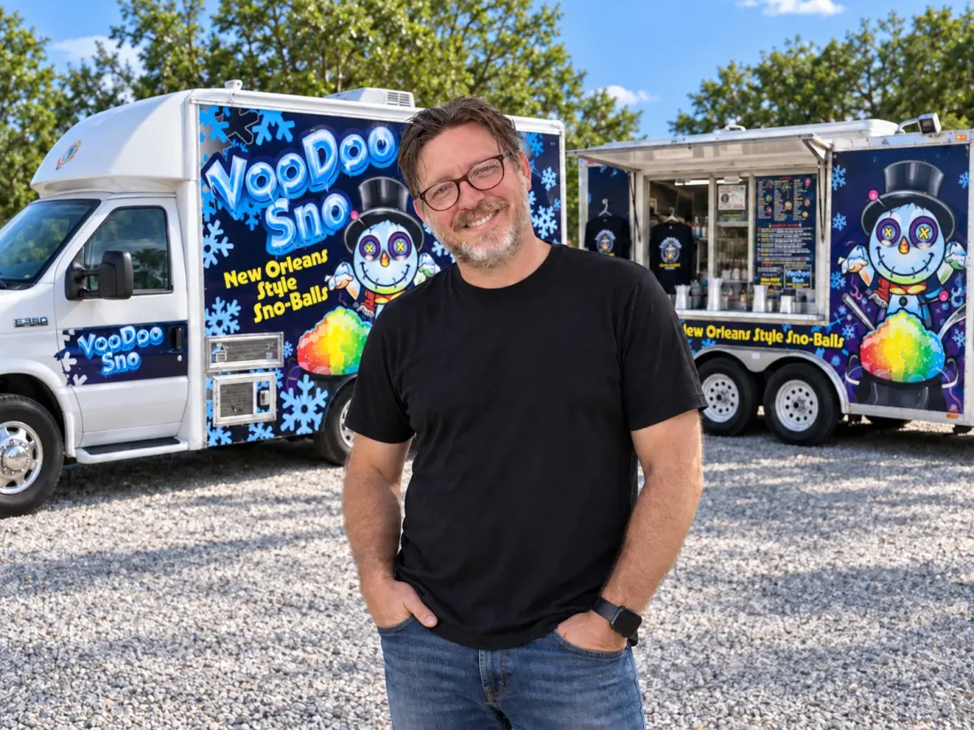 Chris Bailey standing in front of the VooDoo Sno truck and trailer on a gravel lot.